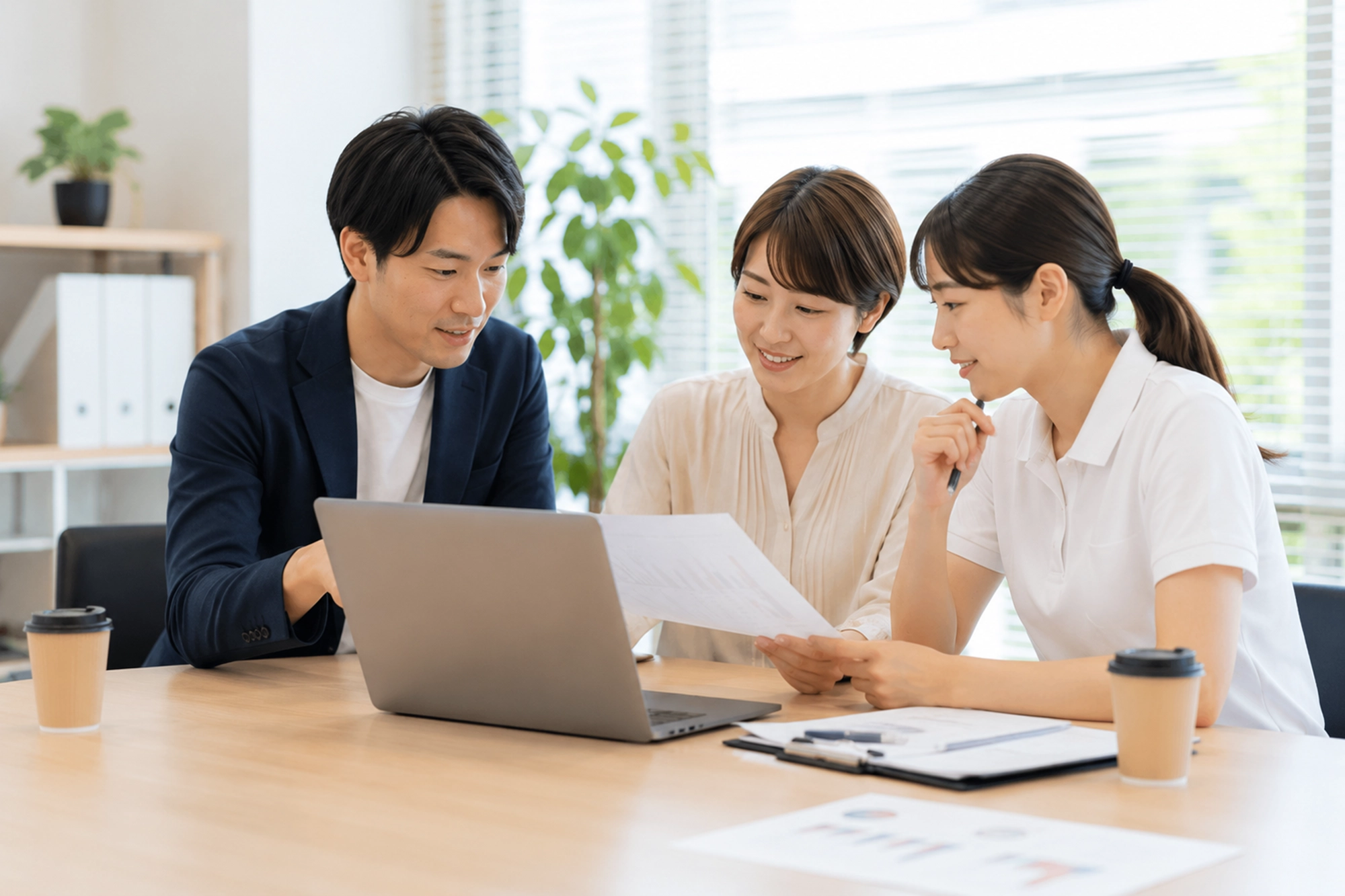 介護職員と担当者がパソコンと資料を囲んで相談する様子